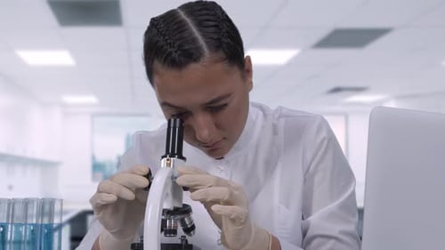 Woman Scientist Uses Microscope then Types on Laptop