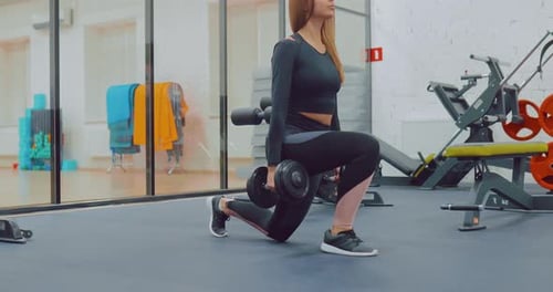 Woman Doing Dumbbell Lunges at the Gym