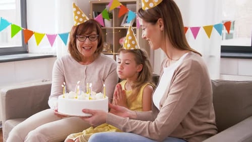 Family Celebrates Girl's Birthday Blowing Out Candles