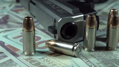 Pistola y balas en billetes de cien dólares