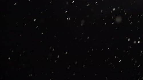Schnee fällt im Winter über den dunklen Nachthimmel