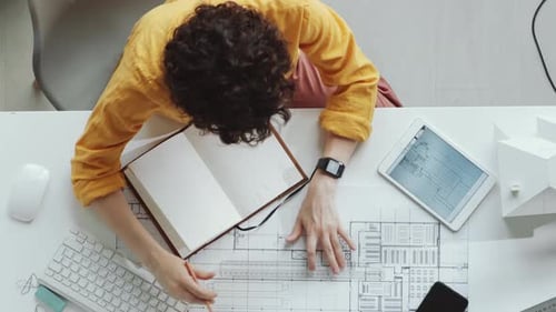 Architect Working on Blueprints at Desk