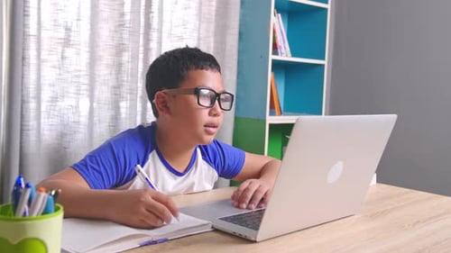 Boy Studying and Taking Notes at Computer