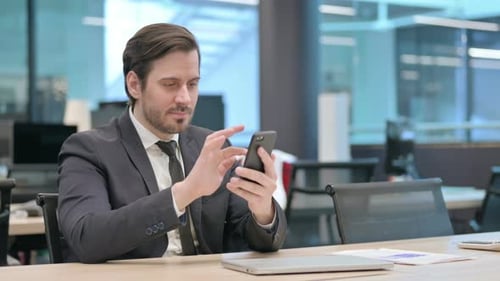 Man in Suit Celebrates Success on Mobile Phone