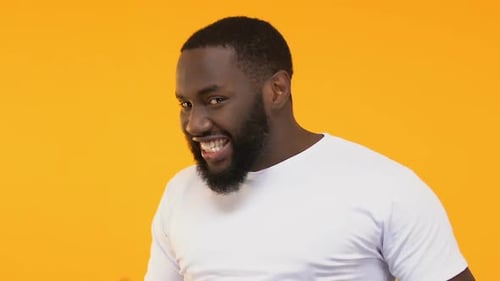 Smiling Man with Beard Gesturing on Orange Background
