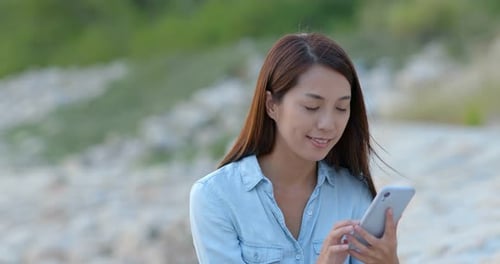 Woman Using Smartphone on Sunny Beach