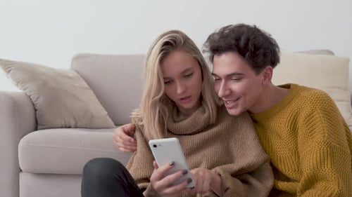 Young Couple Using Phone Together at Home