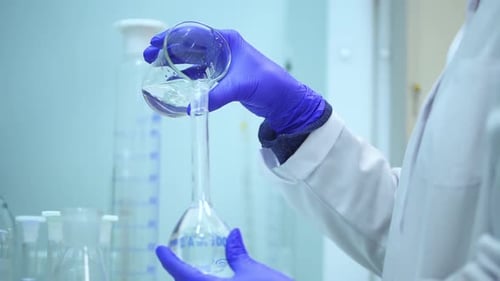 Laboratory Scientist Carefully Pours Liquid into Flask
