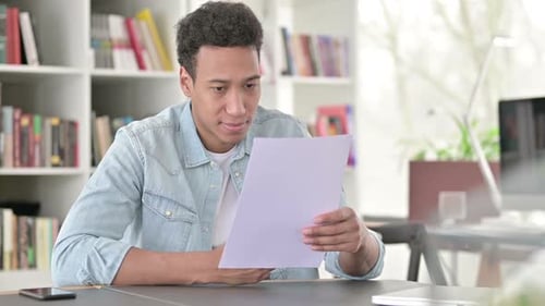 Young African American Man Reading Papers in Office