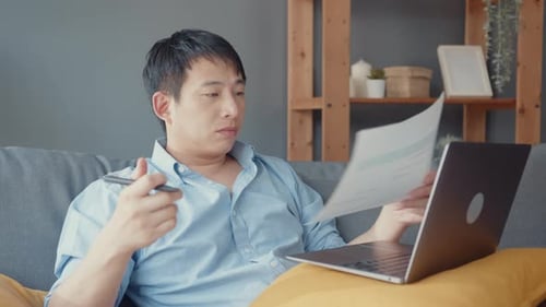 Man Working From Home on Laptop and Paper