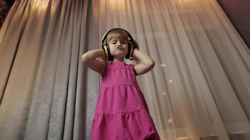 Little Child Girl in Wireless Headphones Enjoying Listen Music. Dancing at Home