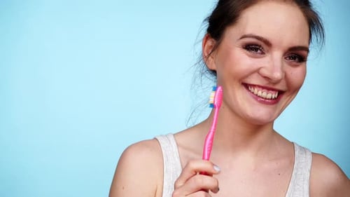 Smiling Woman Holding a Pink Toothbrush
