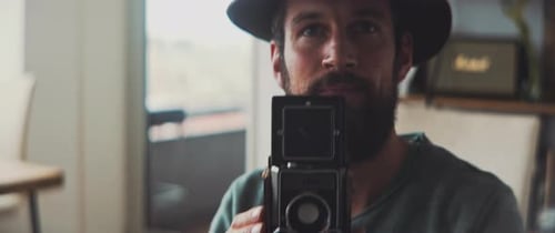 Man Using Vintage Camera Indoors in Daytime