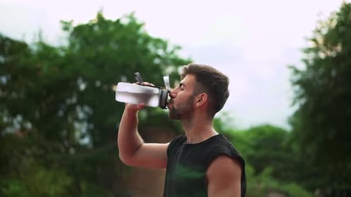 Man Drinking Water After Workout in Park