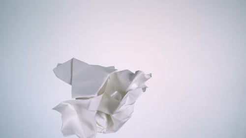 Crumpled Paper Slowly Rotating on White