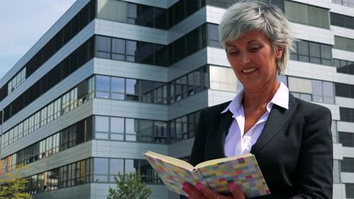 Business Middle Age Woman Reads Some Book - Company Building in the Background