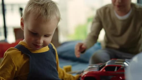 Two Boys Playing with Red Toy Car Indoors