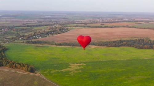 Red Heart Balloon Drifting Above Countryside