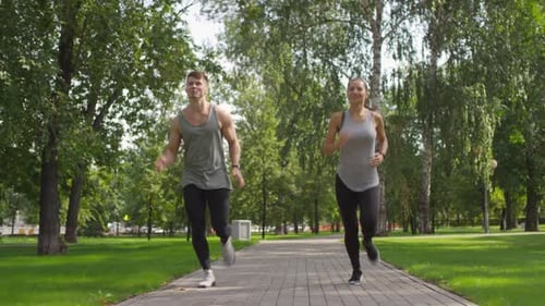 Athletic Caucasian Couple Jogging in Park on Summer Day
