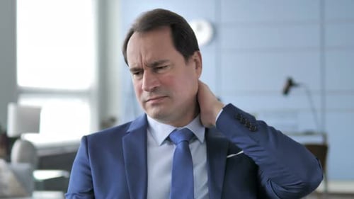 Man Massaging Neck in Office Setting