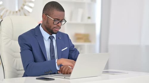 Thoughtful Young Adult Working at Computer in Office