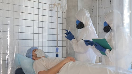 Doctor in Protective Suit Tending Patient