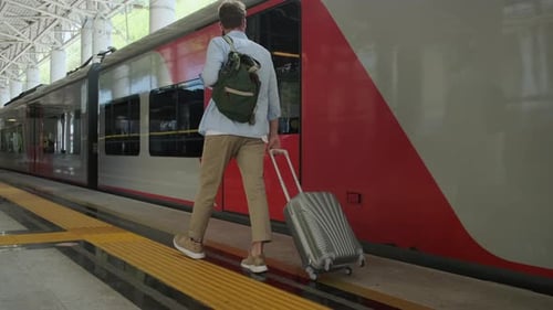 Young Man Walking Along the Platform at the Train Station