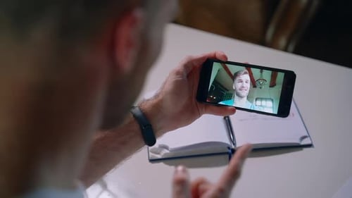 Man Video Chats on Smartphone Indoors