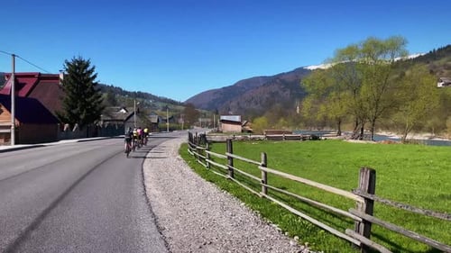 Gruppe von Radfahrern, die auf der Straße durch Berge fahren.