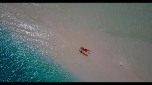 Boy and girl tanning on relaxing bay beach vacation by blue green water and white sandy background o
