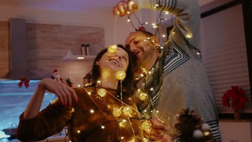 Homme et femme emmêlés dans une guirlande de lumières scintillantes