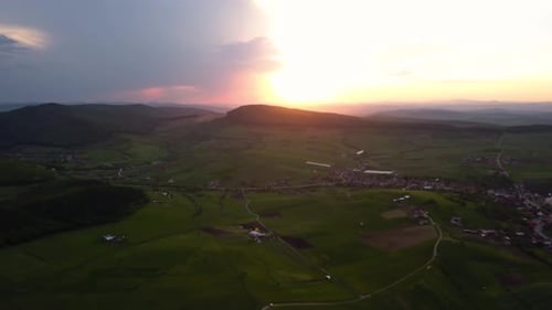 Panorama-Luftaufnahme eines wunderschönen Sonnenuntergangs über offenem Land mit grünen Wiesen und Feldern, Siebenbürg