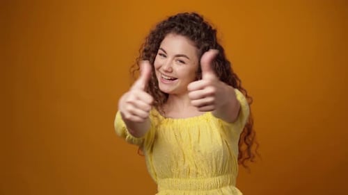 Woman Gives Two Thumbs Up on Orange Background