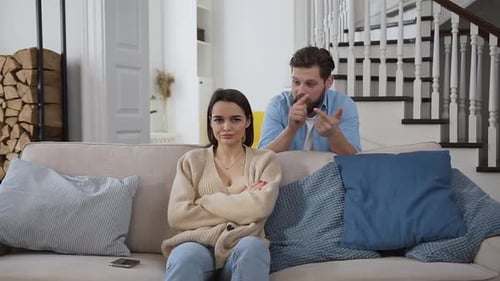 Sad Woman Sitting on the Sofa Nad Listening How Her Bearded Husband Listing Problems
