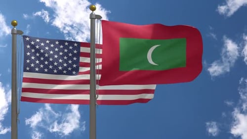 United States and Maldives Flags Waving in Wind Against Blue Sky