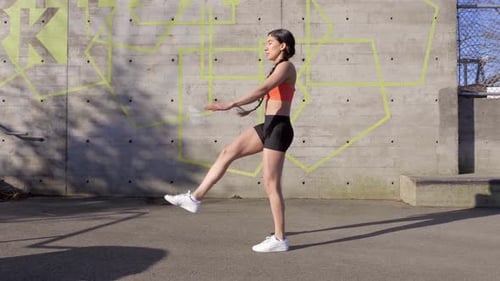 Jovem mulher faz chute alto com rotina de exercícios de braço estendido, perfil Wide Shot