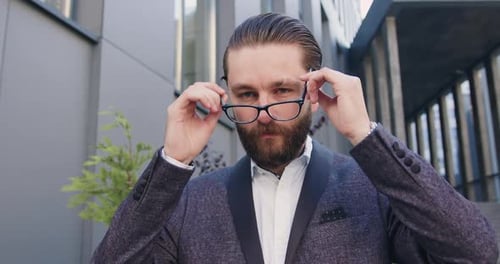 hombre en traje de negocios que se pone sus gafas mientras mira a la cámara con una bonita sonrisa