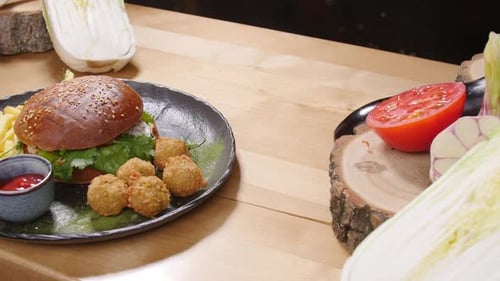 Burger, Fries, and Vegetables on a Wooden Table