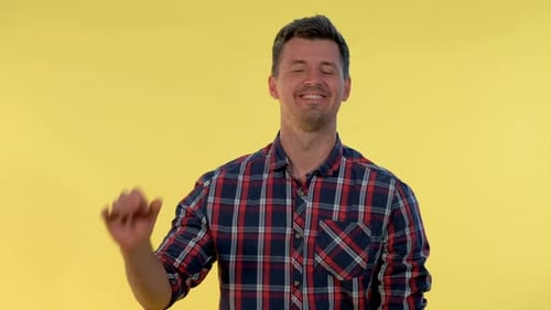 Smiling Man Gestures OK Symbol on Yellow Background