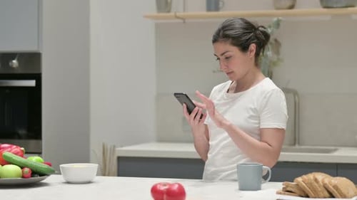 Woman Using Mobile Phone in Modern Kitchen