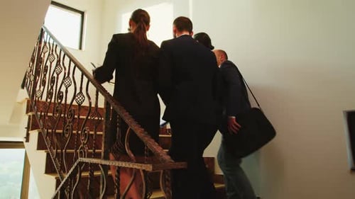 Professionals walking up stairs inside a house