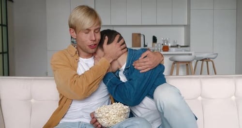 Loving Male Couple Watching a Scary Movie at Home