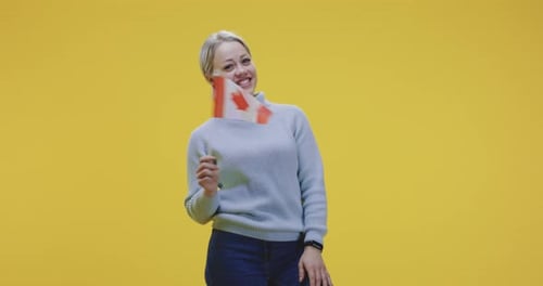 Smiling Woman Holding Canadian Flag on Yellow Background