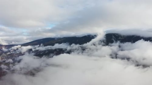 Flight Through Blue Sky with Clouds Over Mountain