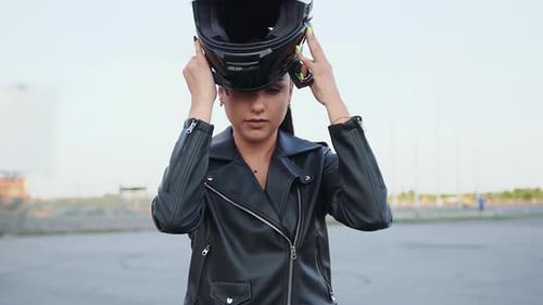 Woman Puts on Motorcycle Helmet in Urban Setting