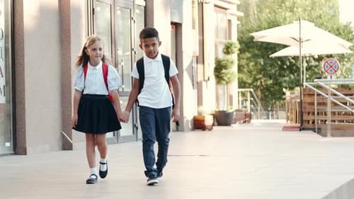 Kinder mit Rucksäcken kommen von der Schule zurück und lächeln.