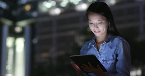 Woman use of tablet computer in city at night