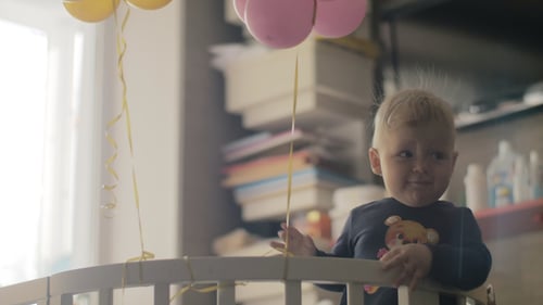 Niña juguetona con globos en la cuna