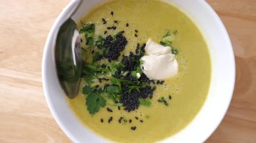 Creamy Green Soup Served with Herbs and Seeds