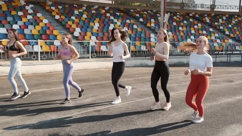 Two Pretty Sportswomen Running on Stadium on Sunset